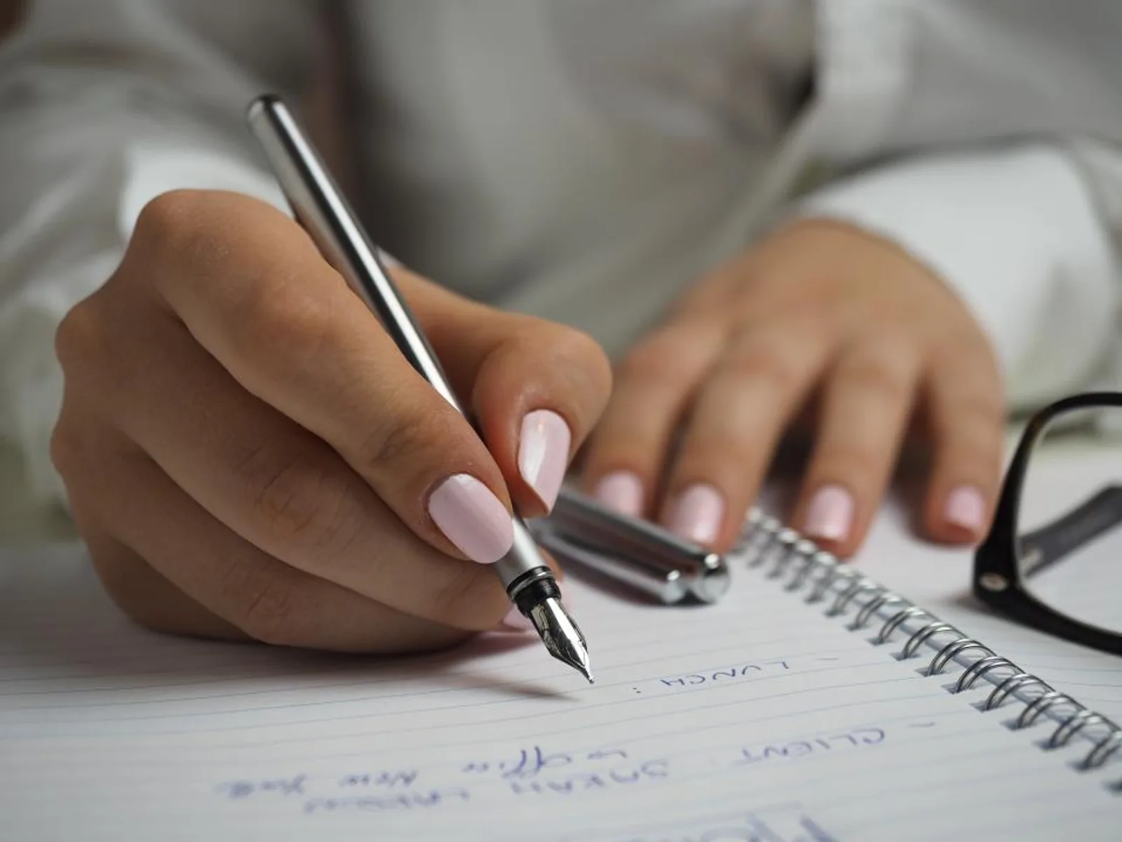 A hand writing with a fountain pen in a spiral notebook