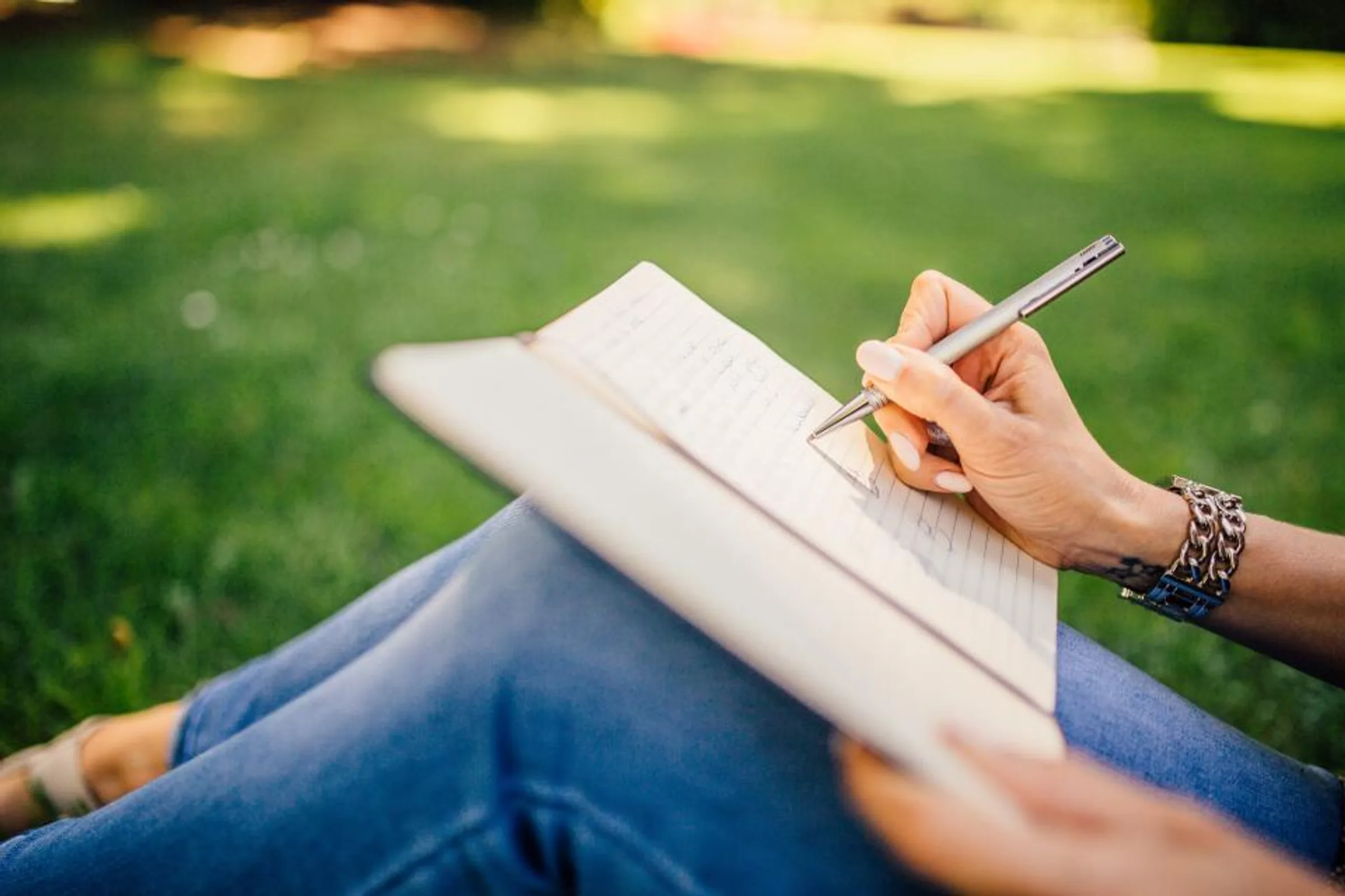 A woman writing in a notebook on the grass