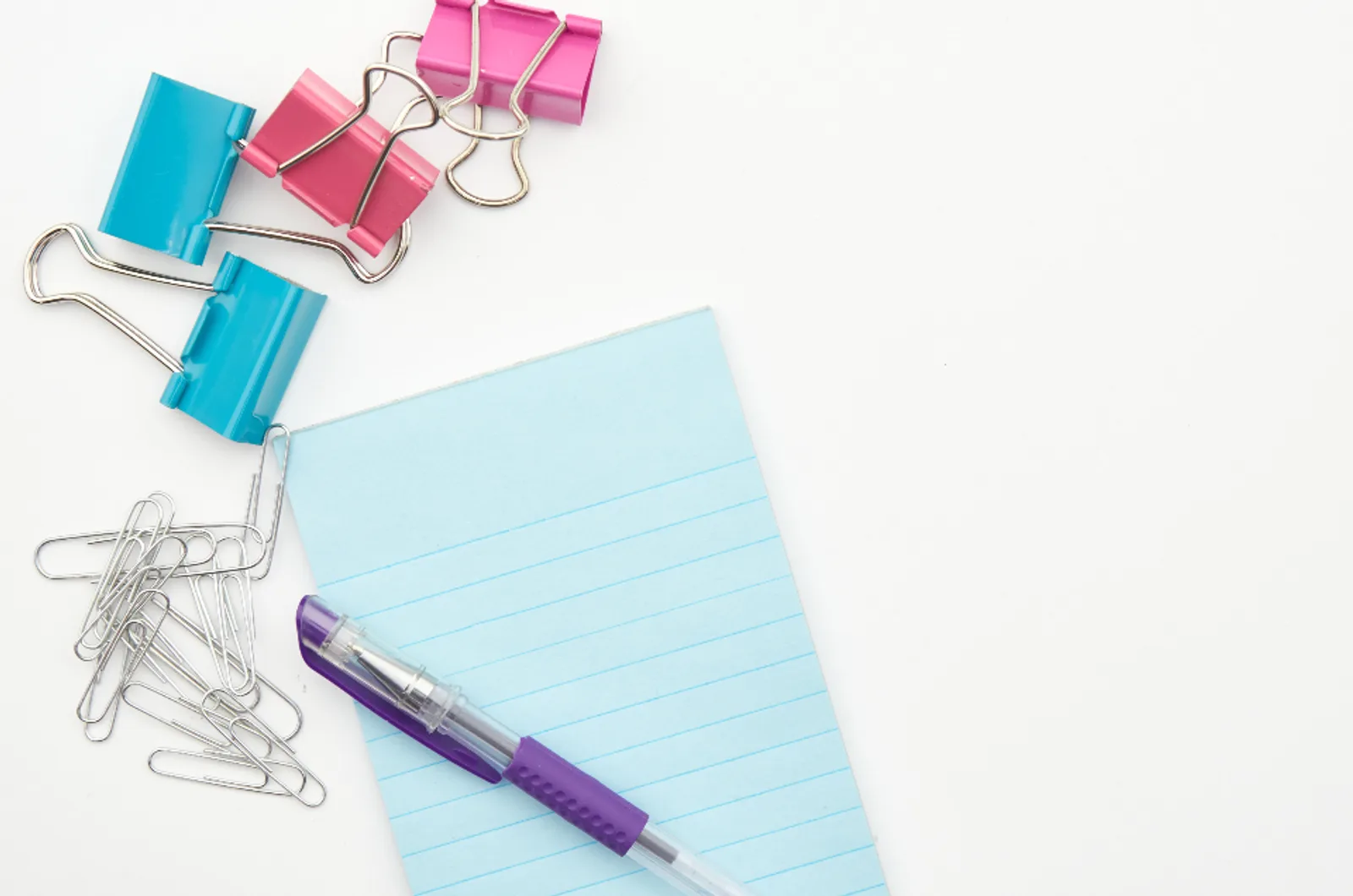 Binder clips, paper clips and a pen on a notepad